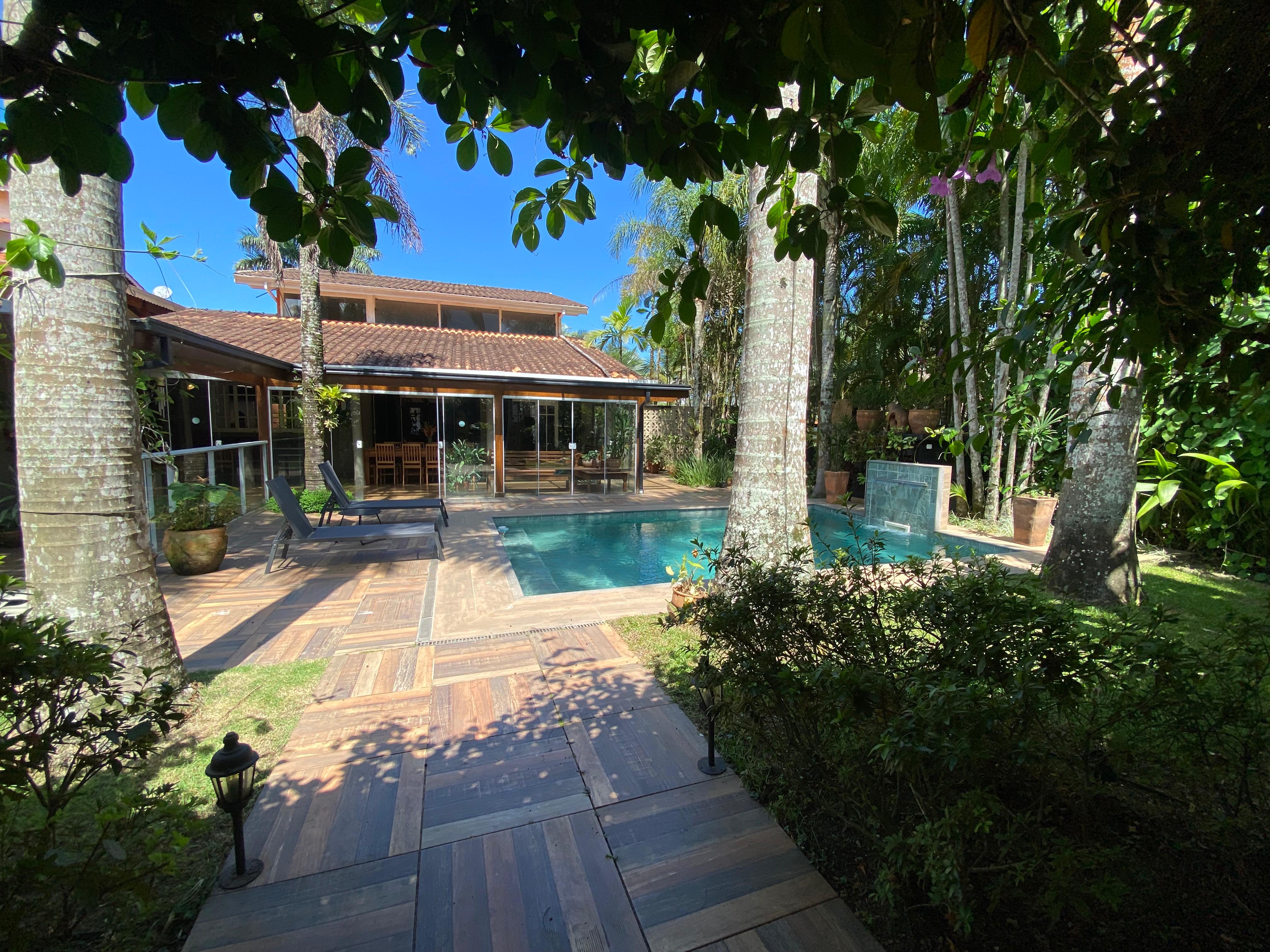 Piscina da Casa das Palmeiras cercada pelo jardim tropical